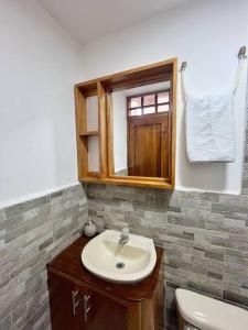 a bathroom with a sink and a mirror and a toilet at El Encanto de Mimi in Puerto Ayora