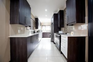 una cocina con armarios de madera oscura y electrodomésticos blancos en URlyfstyle 5 bedrooms near OR Tambo international Airport en Kempton Park