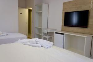 um quarto de hotel com duas camas e uma televisão de ecrã plano em PEDREIRA FLAT HOTEL em Pedreira