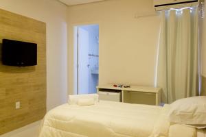 um quarto com uma cama e uma televisão na parede em PEDREIRA FLAT HOTEL em Pedreira