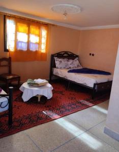 a bedroom with a bed and a table on a rug at Hôtel Kasbah Telouet in Telouet