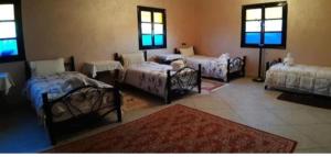 a room with four beds and a room with windows at Hôtel Kasbah Telouet in Telouet