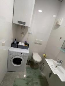 ein weißes Badezimmer mit einer Waschmaschine und einem Waschbecken in der Unterkunft JS Design Apartment in Graz