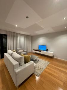 uma sala de estar com um sofá branco e uma televisão em Leonor Seaview Apartment em Funchal