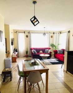 ein Wohnzimmer mit einem roten Sofa und einem Tisch in der Unterkunft The White Dove - At Migaa Golf Estate in Kiambu