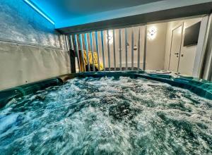 a large jacuzzi tub in a room with water at Luxor - Jacuzzi&Cozy Apartments in Sibiu