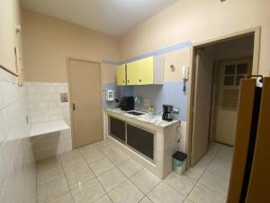 a small kitchen with yellow cabinets and a sink at Apartamento no coração de Petrópolis in Petrópolis