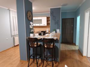 a kitchen with a table with stools and a counter top at Apartman Jela in Borča