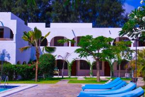 a white building with blue rafts in front of a pool at Kaleb's Beachfront Serviced Studio Apartments in Malindi