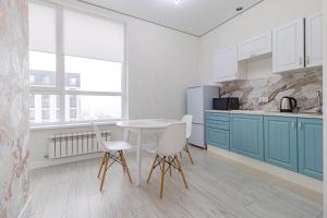 a kitchen with blue cabinets and a table and chairs at Apple City Apartments -161, ЭКСПО, Mega Silky Way in Prigorodnyy