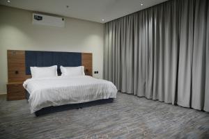 una camera da letto con un grande letto bianco e tende di شقة فندقية Elite Corner a Riyad