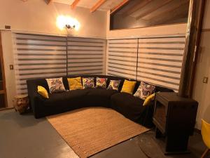 un sofá negro con almohadas en la sala de estar en Casa para 9 personas a 30 metros del lago Caburgua !, en Caburgua