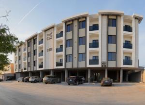 ein großes Gebäude mit Autos auf einem Parkplatz in der Unterkunft شقة فندقية Elite Corner in Riad
