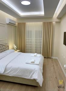 een slaapkamer met een groot wit bed en een raam bij Vila Mete Apartment's in Korçë