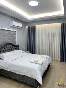 een slaapkamer met een groot bed met witte lakens bij Vila Mete Apartment's in Korçë