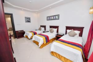 2 camas en una habitación con paredes blancas en Aseel Alsharq Hotel, en Riad