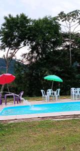 - une piscine avec des chaises longues et des parasols dans l'établissement Chácara recanto do sabiá, à Príncipe