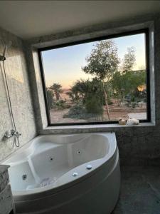 La salle de bains est pourvue d'une baignoire et d'une grande fenêtre. dans l'établissement كعب غزال, à Merzouga