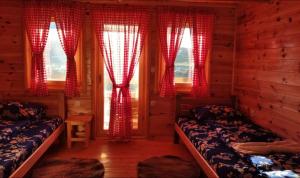 1 dormitorio con 2 camas y ventanas con cortinas rojas en Cottages Jasavić, en Plav