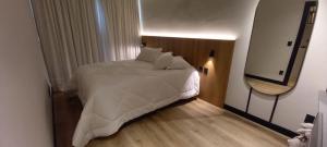een slaapkamer met een wit bed en een spiegel bij Apartamento You Canela 207 in Canela