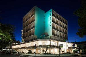 a hotel building with a green lit up sign at Hotel Garden in Cervia