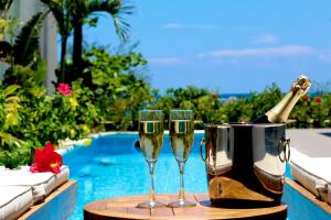 dos copas de champán en una mesa junto a una piscina en Feliz Villa Suite Miyakojima Ueno, en Isla Miyako