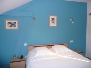 ChevilléにあるHotel Le Saint Aubinの青いベッドルーム1室(壁に2枚の写真が飾られたベッド1台付)