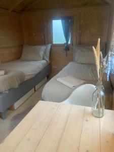 um pequeno quarto com 2 camas e uma mesa de madeira em Pipowagen op Camperplaats Vechtdal em Nieuwleusen