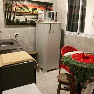 a kitchen with a table and a microwave on top of a refrigerator at Pousada Piscinas Naturais in Porto De Galinhas
