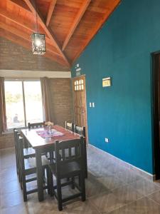 a dining room table with chairs and a blue wall at Departamentos Merlina in El Hoyo