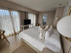 a bedroom with a white bed and a television at Serena Hotel - Punta del Este - Unico sobre la Playa in Punta del Este
