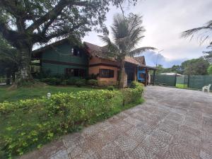 uma casa com uma palmeira ao lado de uma entrada em Chalé Carvalho - Azul em Itapoá