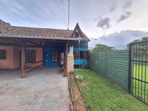 ein Haus mit einem Zaun davor in der Unterkunft Chalé Carvalho - Azul in Itapoa