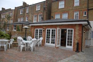 a patio with white tables and chairs in front of a building at Balham Lodge in London