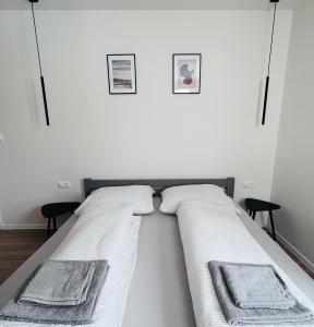 a white bedroom with two beds with towels on them at Nordic House in Závažná Poruba