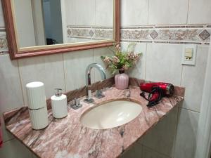a bathroom counter with a sink and a vase of flowers at Apartamento Copacabana Posto 5 in Rio de Janeiro