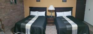 a hotel room with two beds and a lamp at Hotel La Posta in Monclova