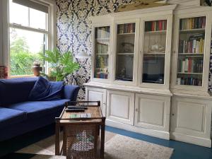 a living room with a blue couch and a book shelf at De Viersprong in Laren