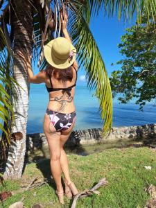 una mujer en bikini y sombrero de pie en una palmera en Horse Cottage en Sarteneja