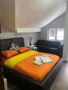 - une chambre avec un grand lit et une couverture orange dans l'établissement Villa Tino Omorani, à Veles