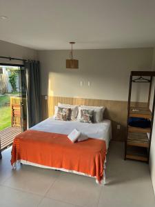 a bedroom with a bed with an orange blanket at Pousada Vielas do Rosa - centrinho da praia do rosa in Praia do Rosa +106 photos