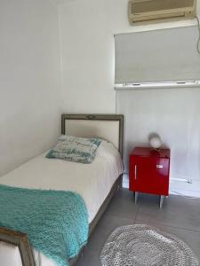 ein kleines Schlafzimmer mit einem Bett und einem roten Nachttisch in der Unterkunft Casa Talar del Lago I in General Pacheco