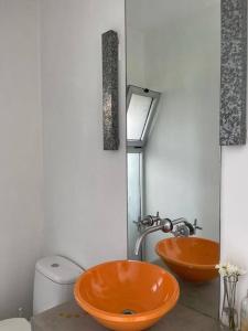 ein Badezimmer mit zwei orangenen Waschbecken und einem WC in der Unterkunft Casa Talar del Lago I in General Pacheco