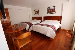 dwa łóżka w małym pokoju ze stołem i tableablishthritisthritis sthritis w obiekcie El SOL HOTEL - URUBAMBA w mieście Urubamba