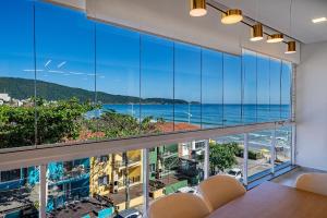 a room with a large window with a view of the ocean at Edifício Solar do Atlântico Beira Mar de Bombas in Bombinhas