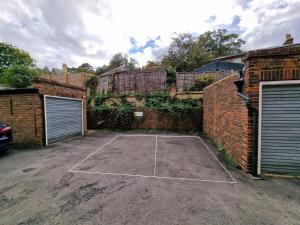 um campo de ténis em frente a uma parede de tijolos em Millmead Apartment in central Guildford with parking em Guildford