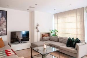 uma sala de estar com um sofá e uma televisão em Spectacular Mews House in Holland Park em Londres