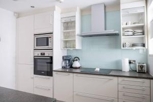 uma cozinha branca com armários e electrodomésticos brancos em Spectacular Mews House in Holland Park em Londres