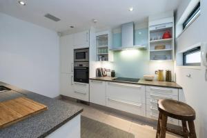 uma cozinha com armários brancos e uma bancada em Spectacular Mews House in Holland Park em Londres