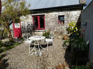 a table and chairs in front of a stone house at Druid cottage in Glendree